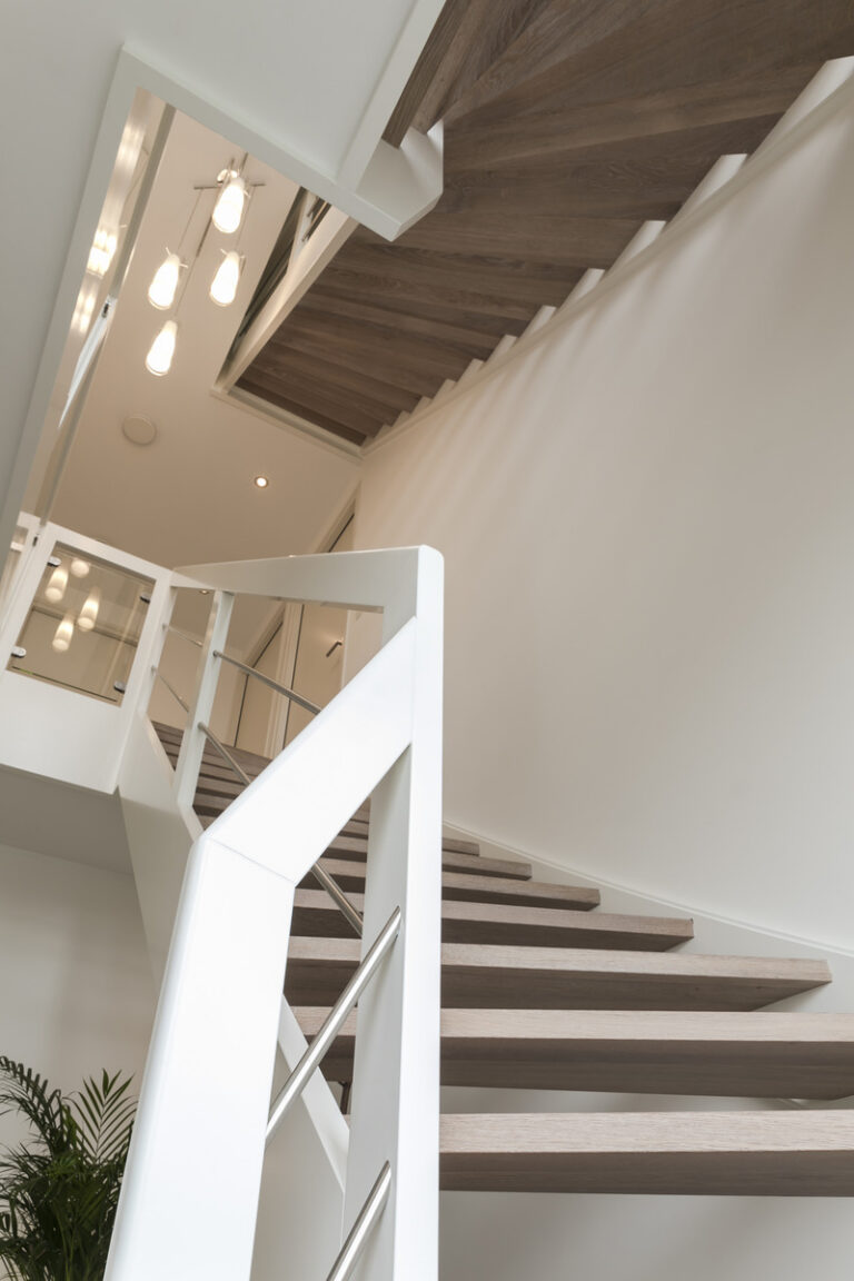 moderne trap,Woensdrecht, Nederland,detailfoto van het bestijgen van de trap,zicht op de treden van deze open trap en de witte beuken balustrade met RVS en glas