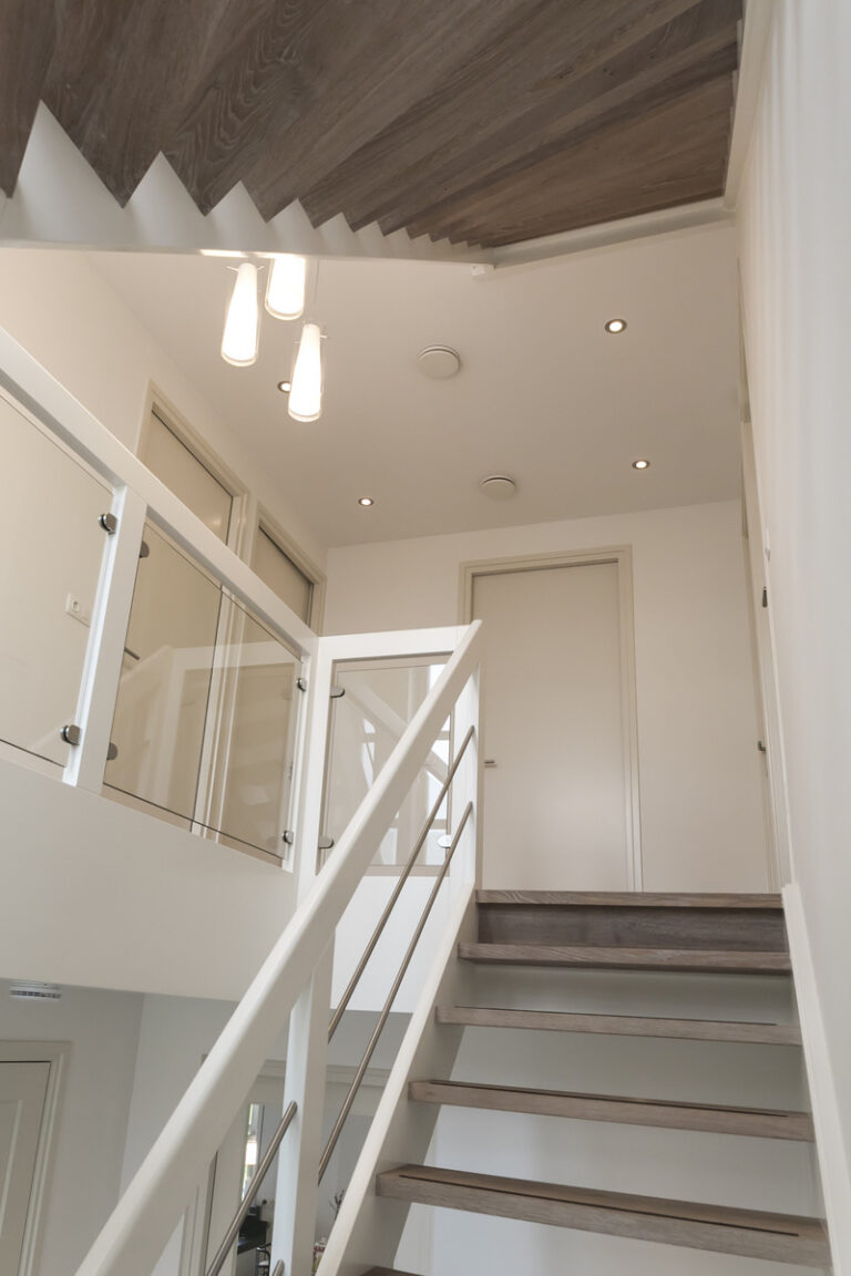 moderne trap,Woensdrecht, Nederland,detailfoto van het bestijgen van de trap naar de verdieping,zicht op glazen balustrade,glas in combinatie met hout,zicht op de RVS (inox) spijlen die evenwijdig lopen met de handgreep van de balustrade