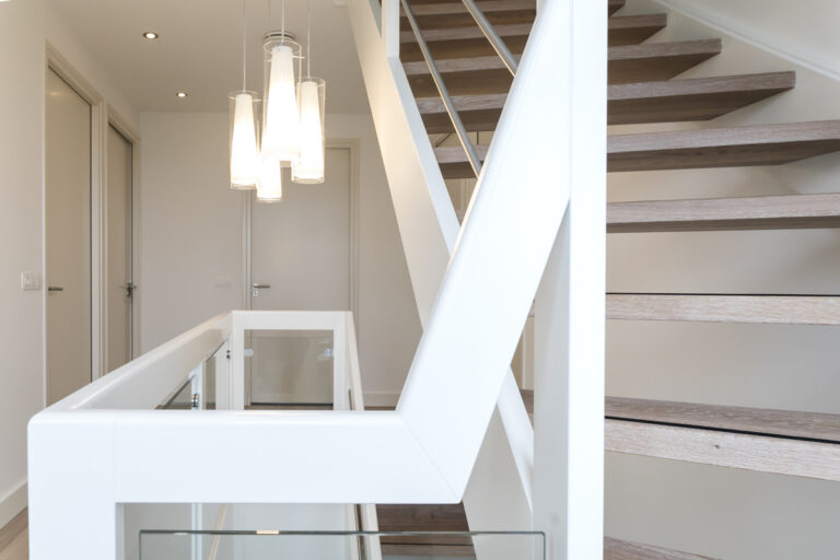 moderne trap,houten trap,open trap,combinatie van witte trapwangen en witte balustrade met houten treden, beukenhout wit geschilderd,detailfoto van de handgreep op de balustrade, en zicht op de treden in eik met antislip,trap in Woensdrecht, Nederland