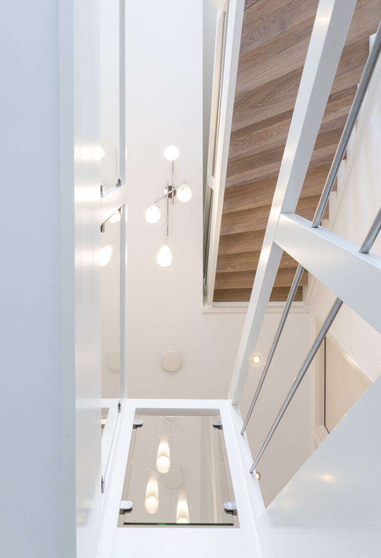 moderne trap,houten trap,witte trap in Woensdrecht, Nederland, zicht op onderkant trap, en zicht op de RVS inox balustrade en de balustrade op de overloop met glazen wand