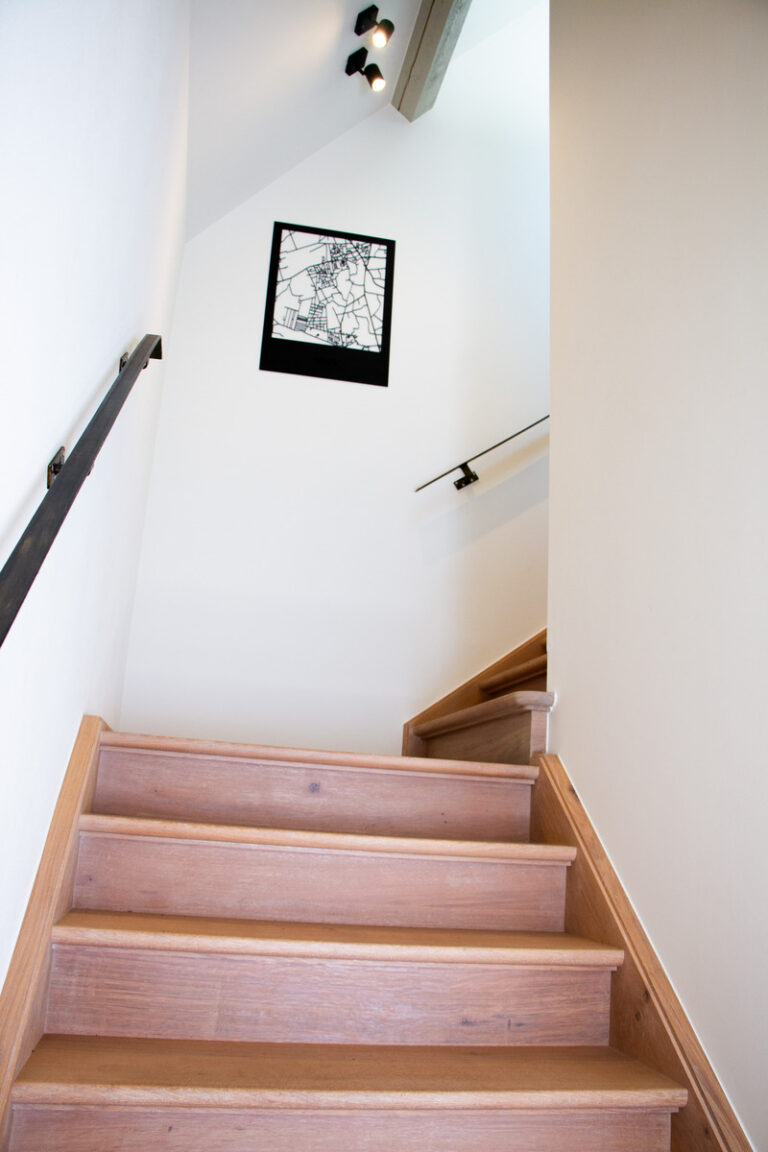 landelijke trap,houten trap,zicht op het bordes,bloktrede,franse eik,licht rustiek,brasserie, restaurant,De Kiekenhoeve,Essen,oude hoeve,gerenoveerd,trap tussen muren,metalen muurgreep,zwart