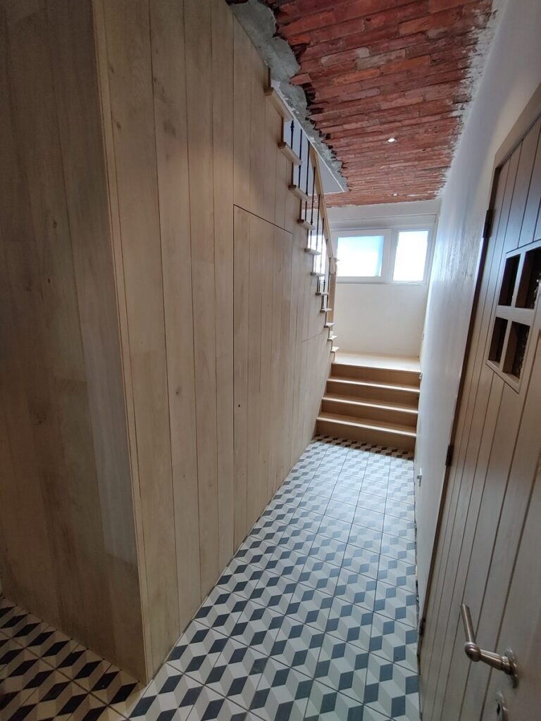 Landelijke trap in Engelse stijl tijdens plaatsing in Kalmthout, zicht op de gang waar deze houten trap staat, zicht op de houten deur die we onder de trap hebben geplaatst