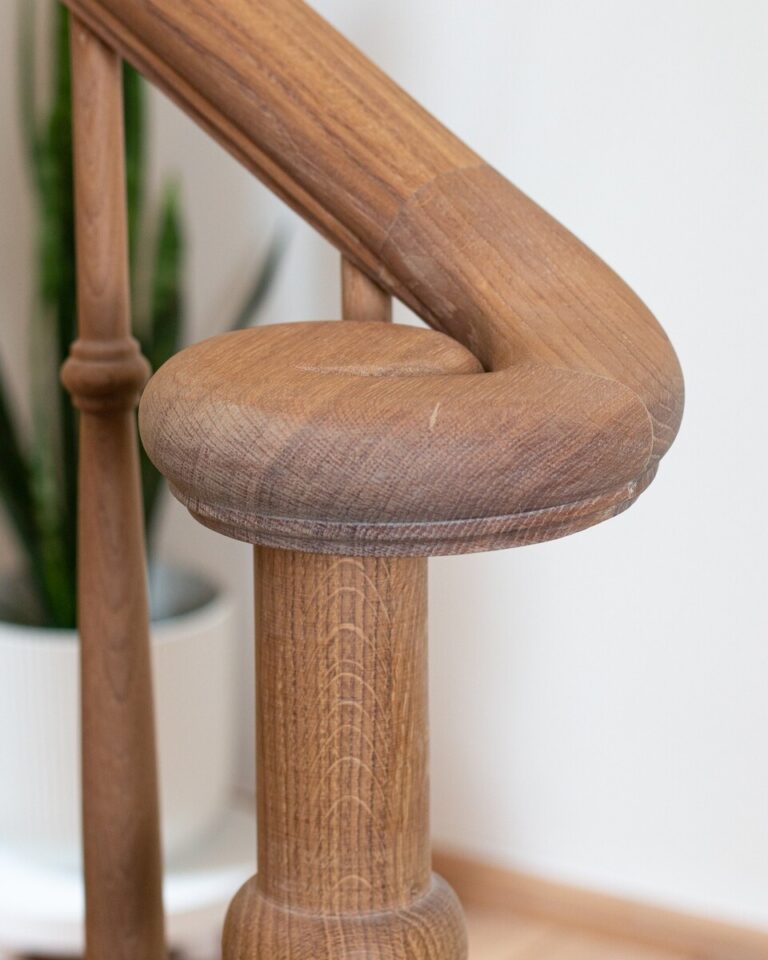 Detail van massieve houten trappaal met klassieke profilering en houtstructuur