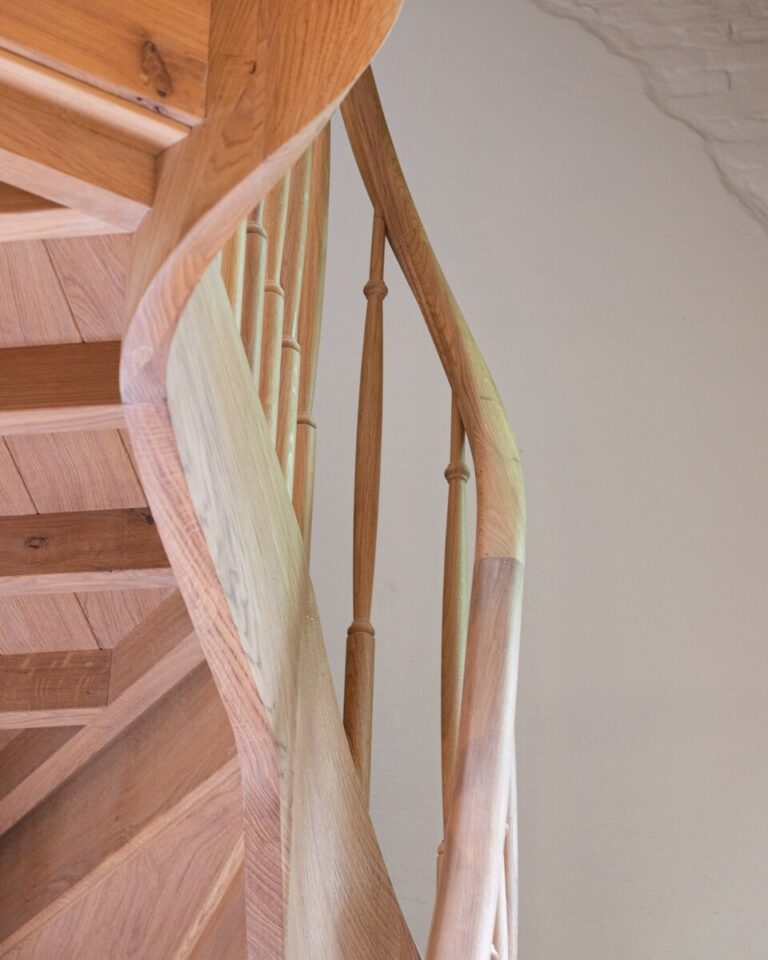 Zijaanzicht van gebogen houten leuning en trapconstructie met sierlijke lijnen